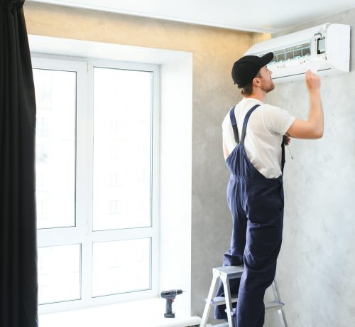 Happy Male Technician Repairing Air Conditioner.